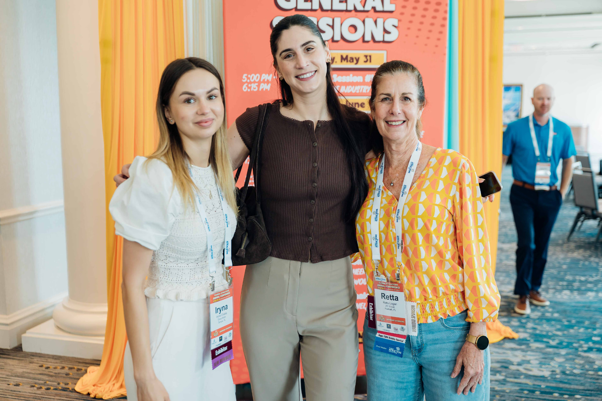 Corporate event photography of three attendees posing in front of a General Sessions signage banner at a conference