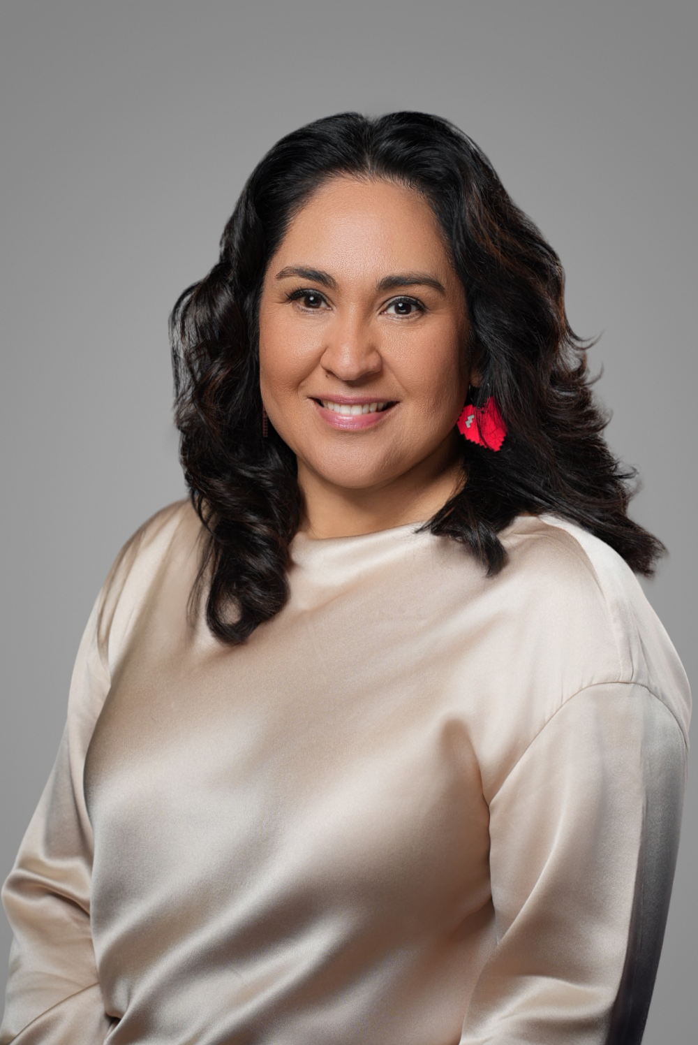 Professional headshot of a businesswoman in a champagne silk blouse on a gray studio backdrop