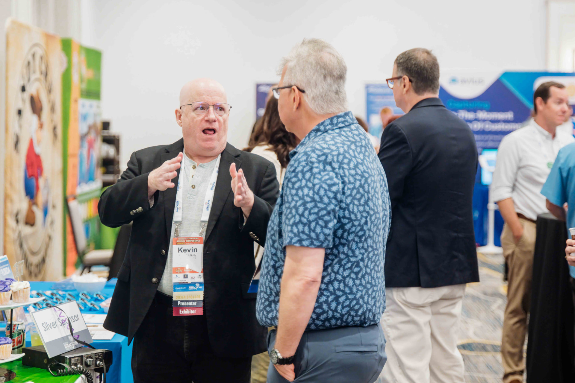 Corporate event photography of a presenter speaking with an attendee at an Orlando association conference expo