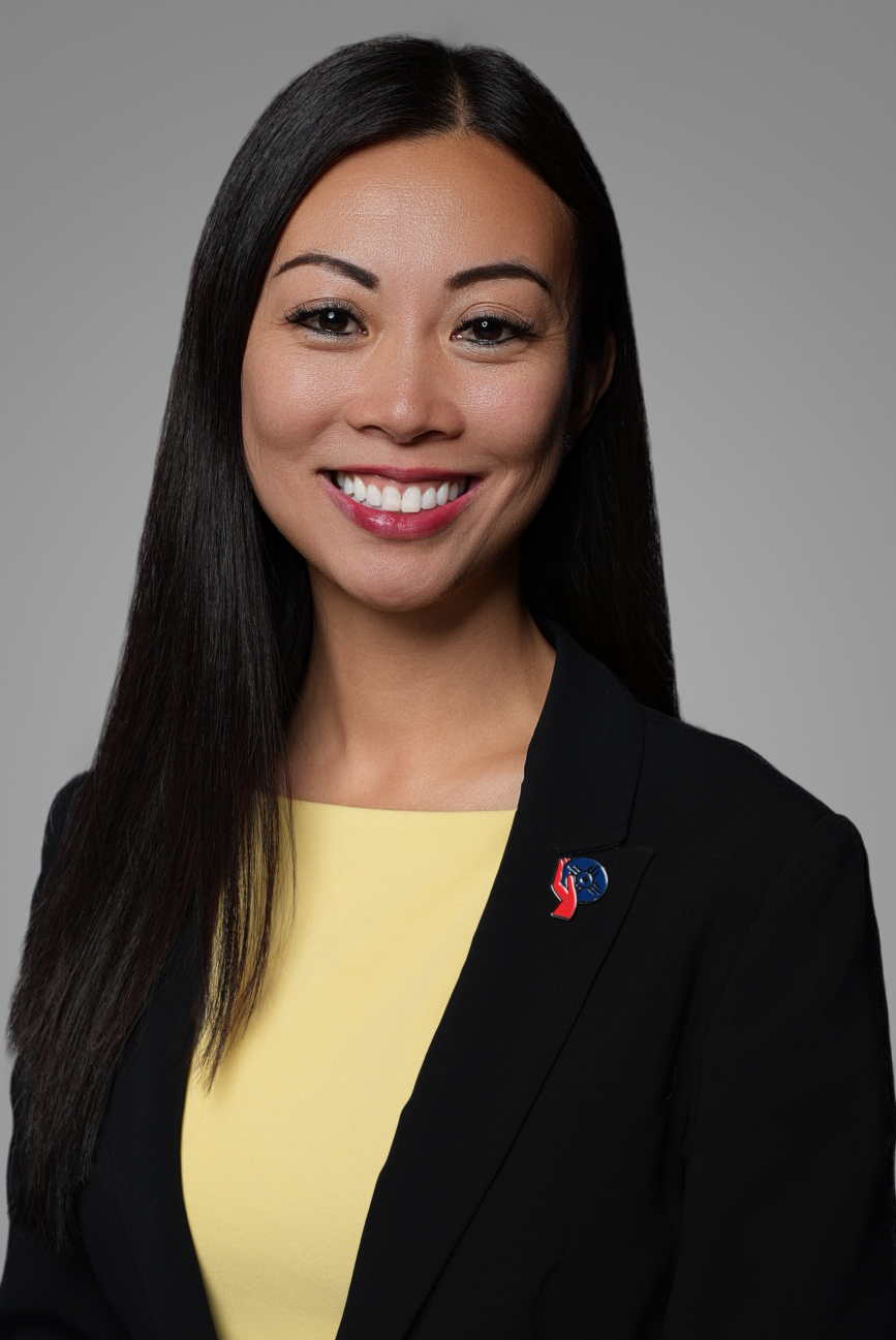 Professional corporate headshot of a businesswoman in a black blazer with a yellow top