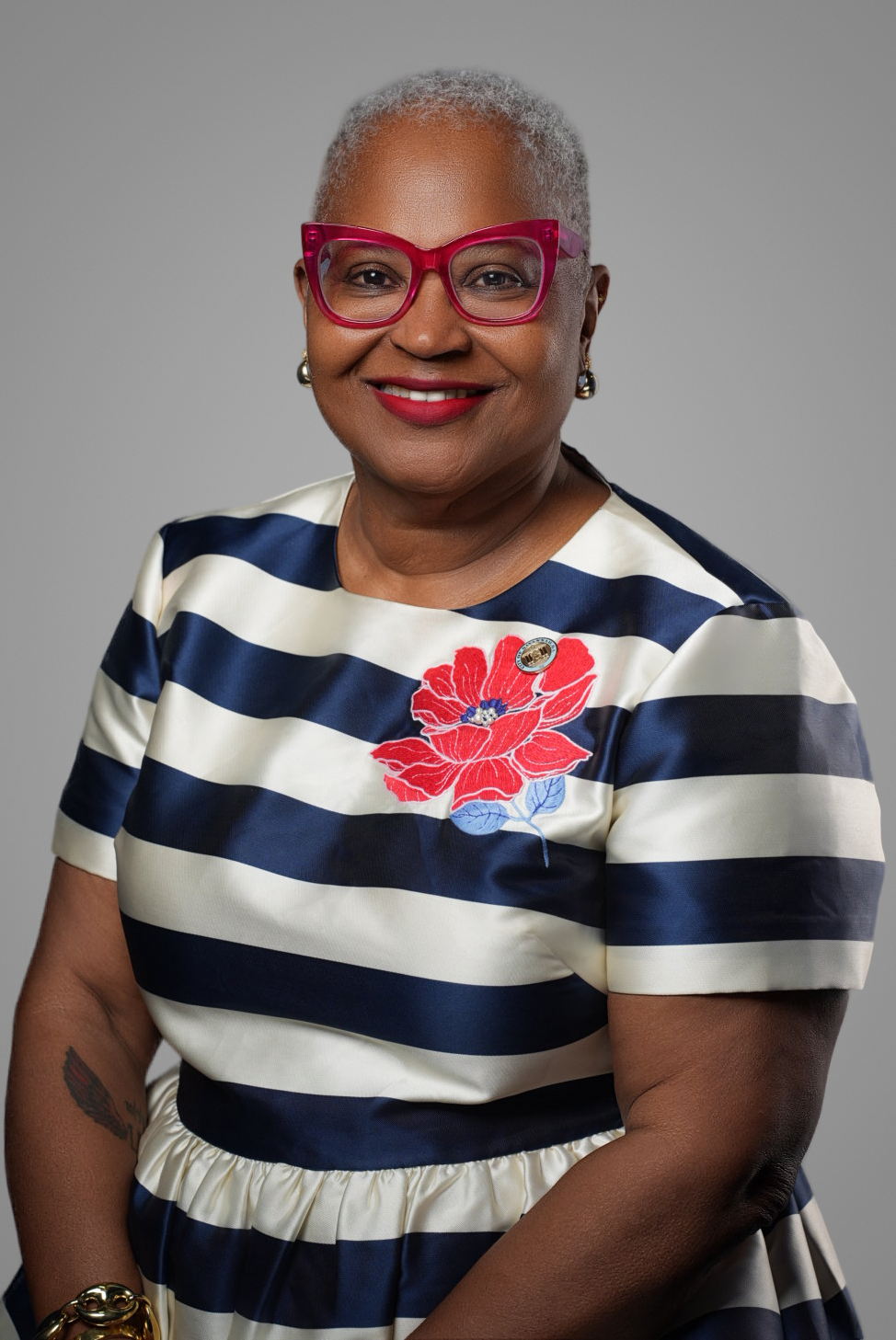 Executive headshot of a woman in red glasses and a navy striped dress captured at a conference headshot station — Endless Visuals Tampa corporate headshots