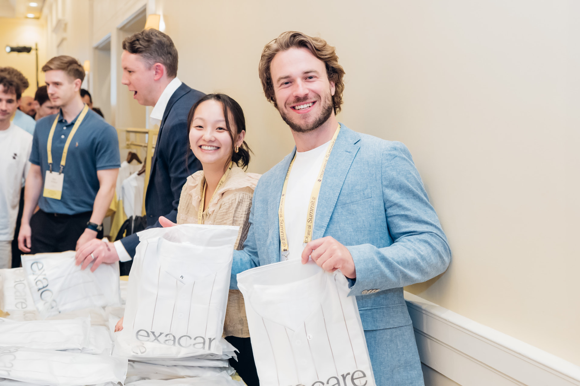 Corporate event photography of two attendees smiling with branded summit gift bags at a hospitality table