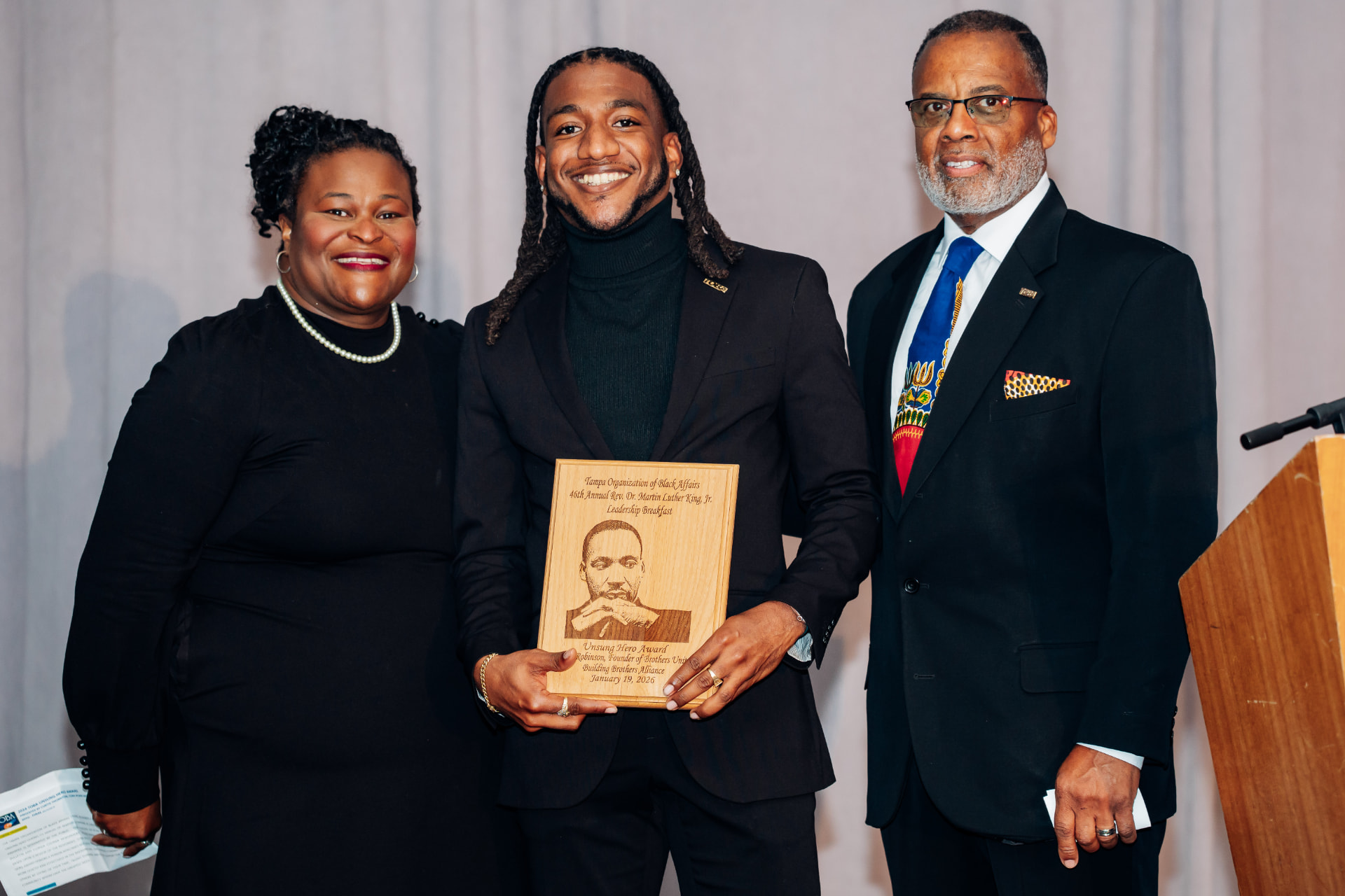 Corporate event photography of an Unsung Hero Award plaque presentation at the Tampa Organization of Black Affairs MLK Leadership Breakfast