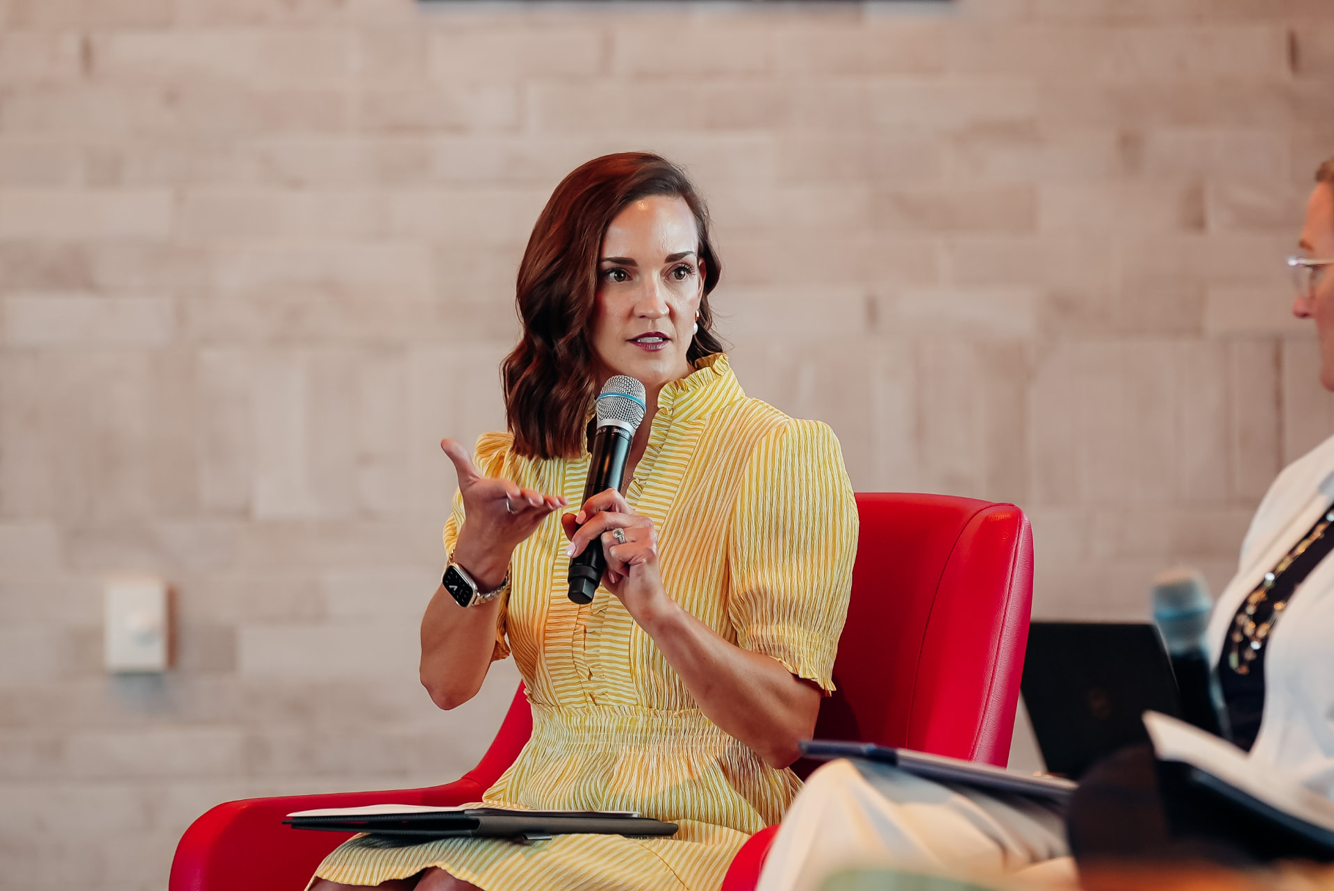 Corporate photography of a panelist speaking into a microphone during a fireside chat