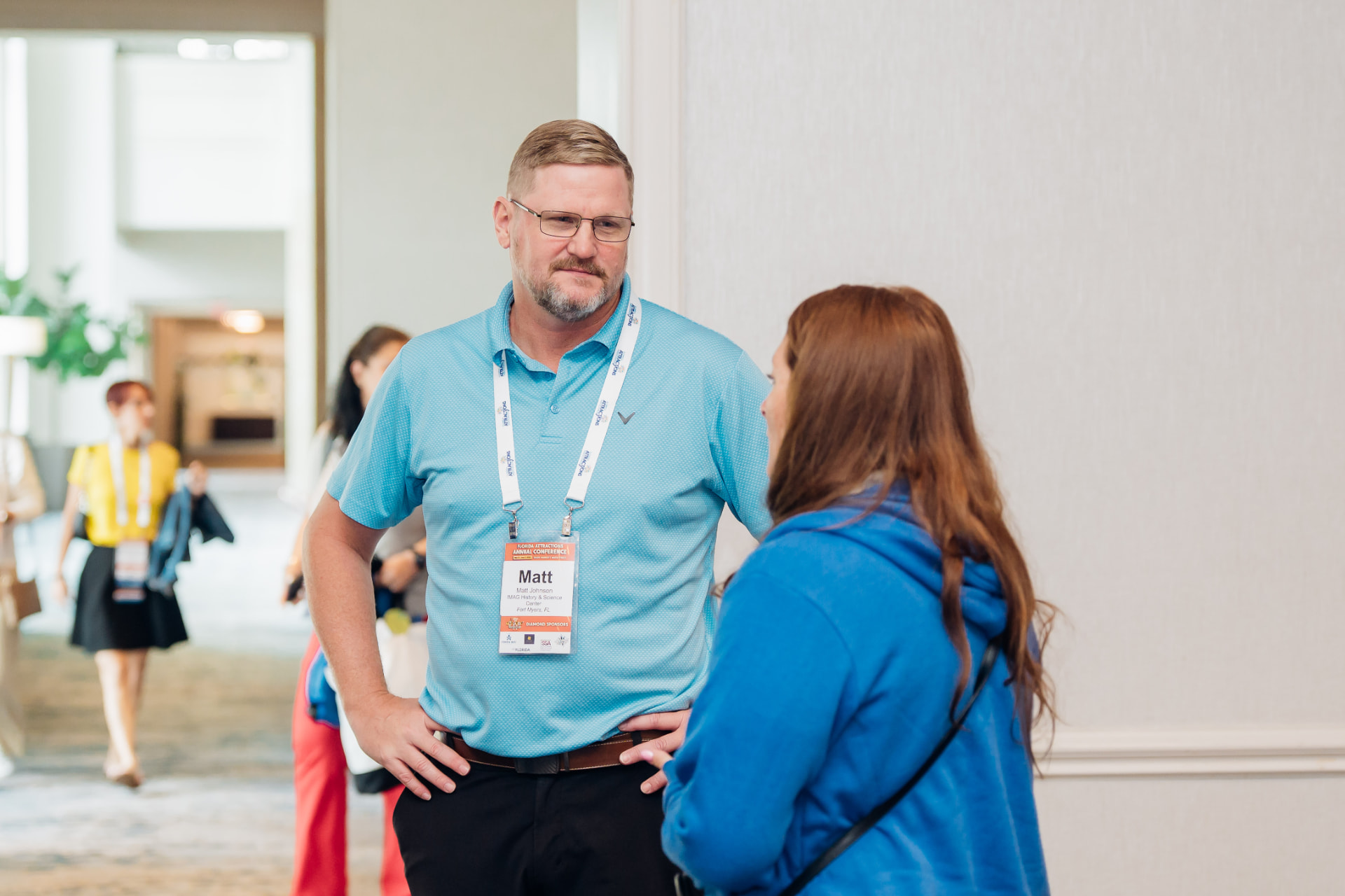 Corporate event photography of two attendees in conversation in a hotel hallway between conference sessions