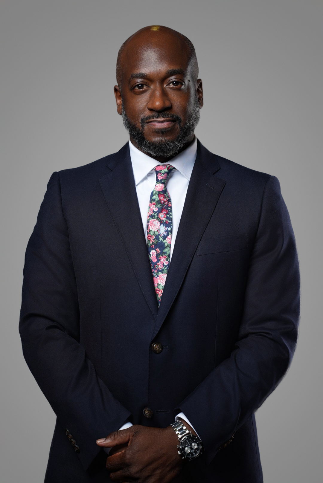 Executive portrait of a businessman in a navy suit with a floral tie on a gray studio backdrop