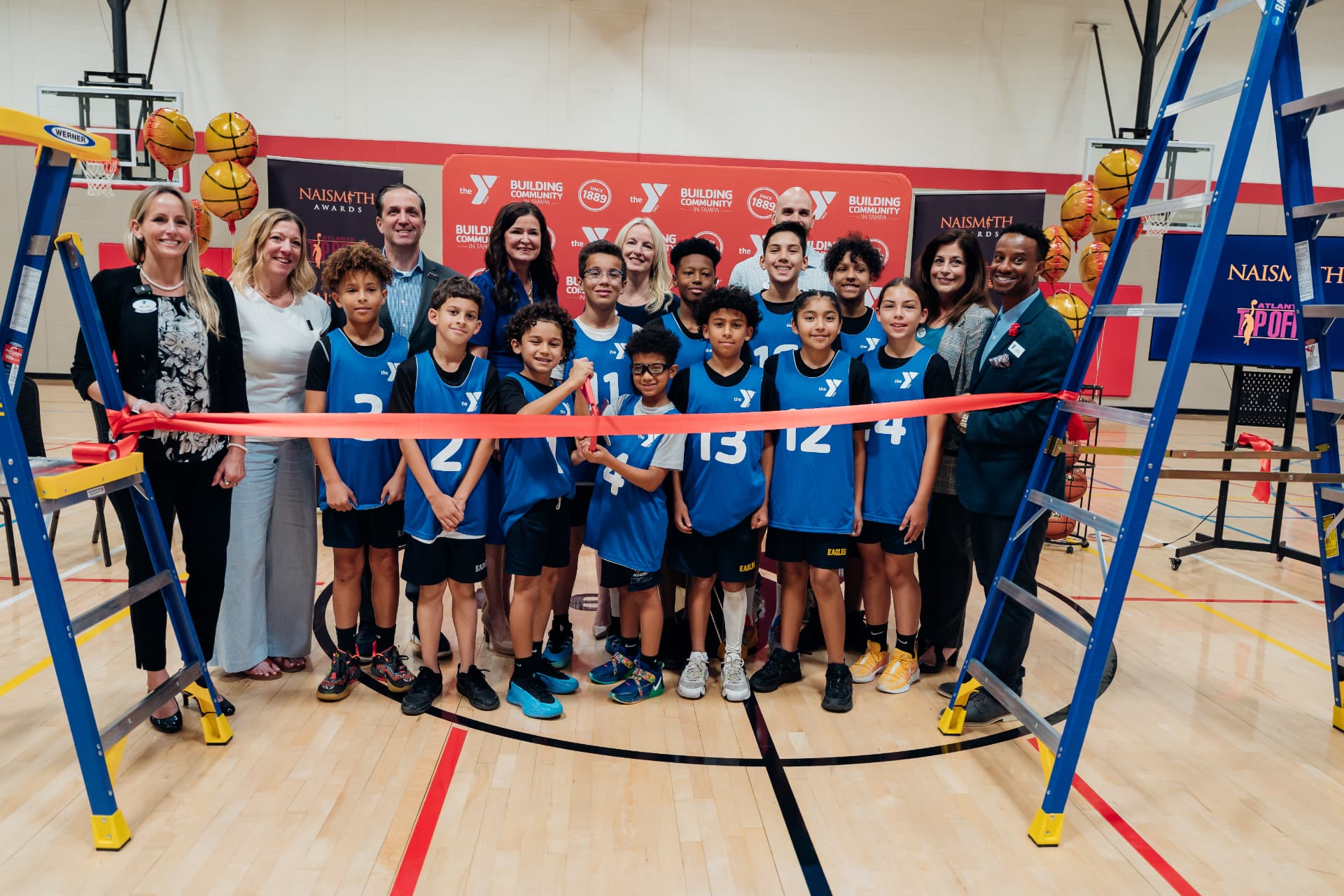 Corporate event photography of a ribbon cutting group photo with youth basketball players at a YMCA Naismith Awards community event in Tampa