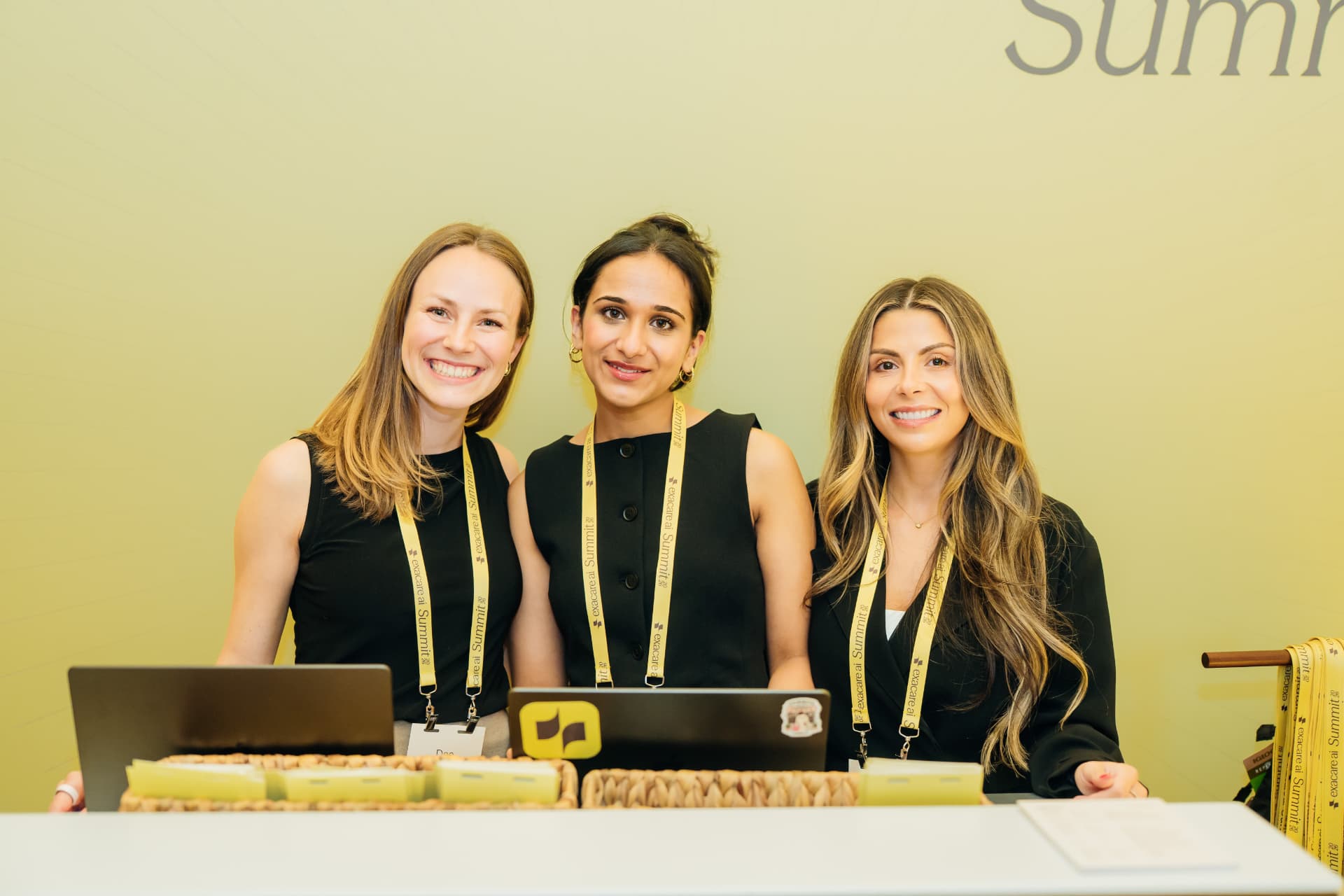 Corporate event photography of a summit registration team welcoming attendees at check-in