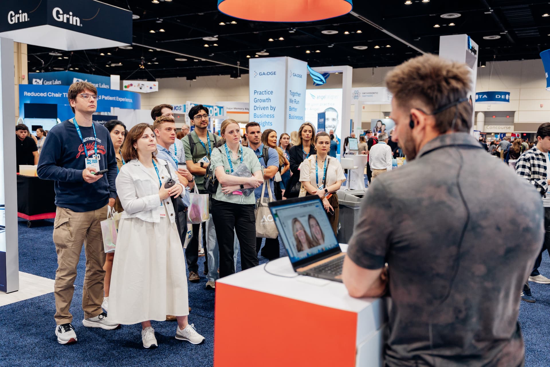 Corporate event photography of attendees gathered around a demo station at a trade show