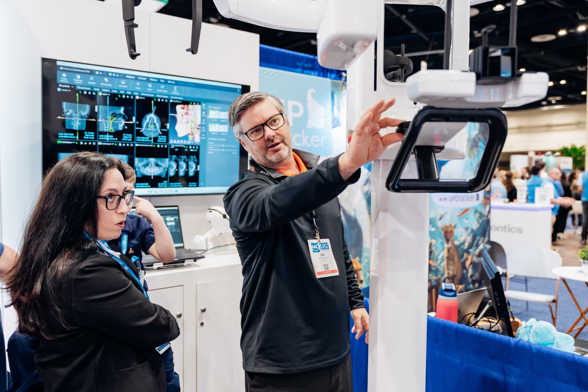 Corporate photography of an exhibitor demonstrating equipment to attendees at an expo booth
