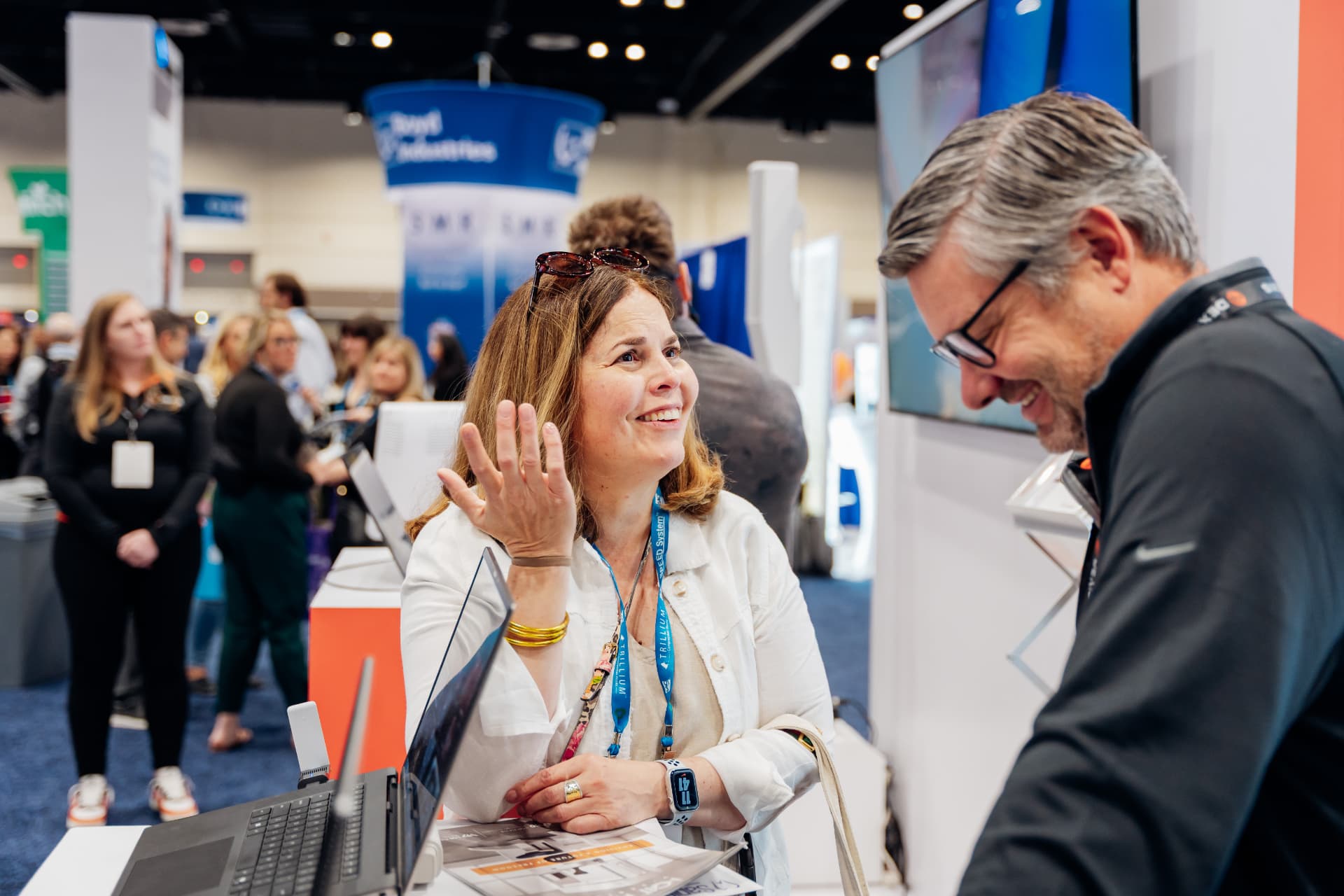 Corporate photography of two professionals laughing during a conversation at an Orlando convention booth
