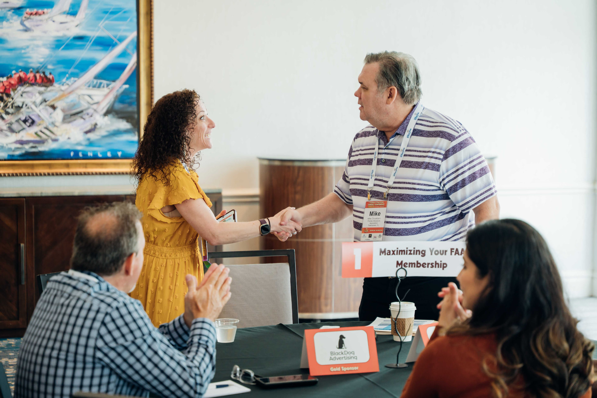 Corporate photography of attendees shaking hands during a conference roundtable session