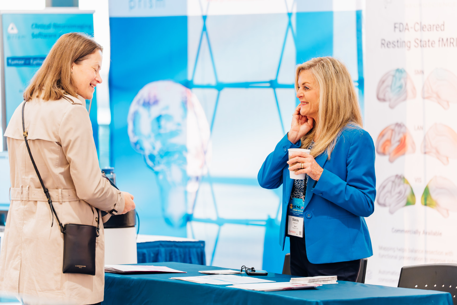Corporate event photography of two attendees talking over coffee at a medical imaging trade show booth