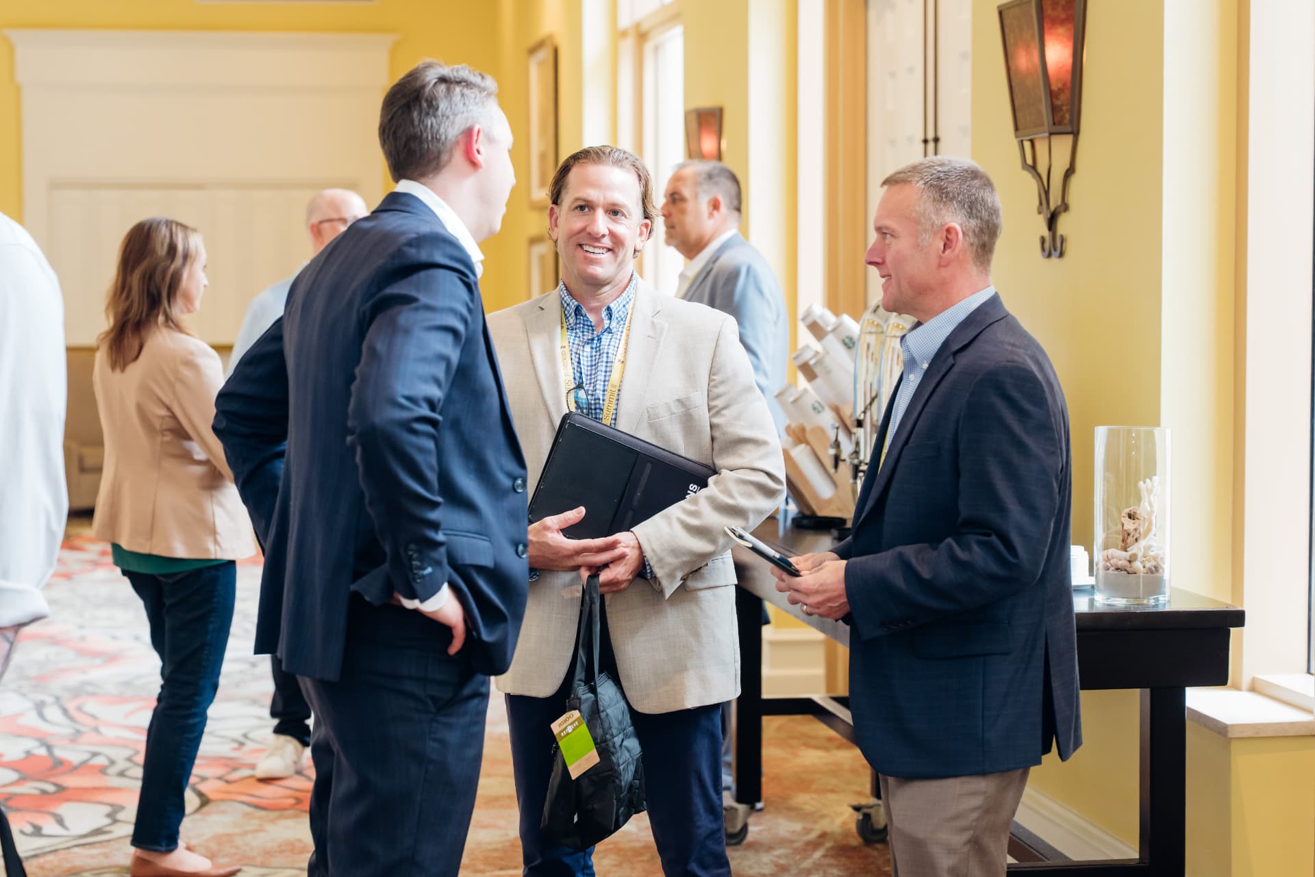 Corporate event photography of executives networking in a hotel corridor at a summit