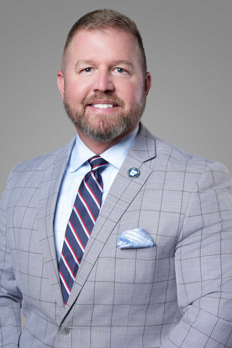 Executive headshot of a business professional in a light gray suit and striped tie