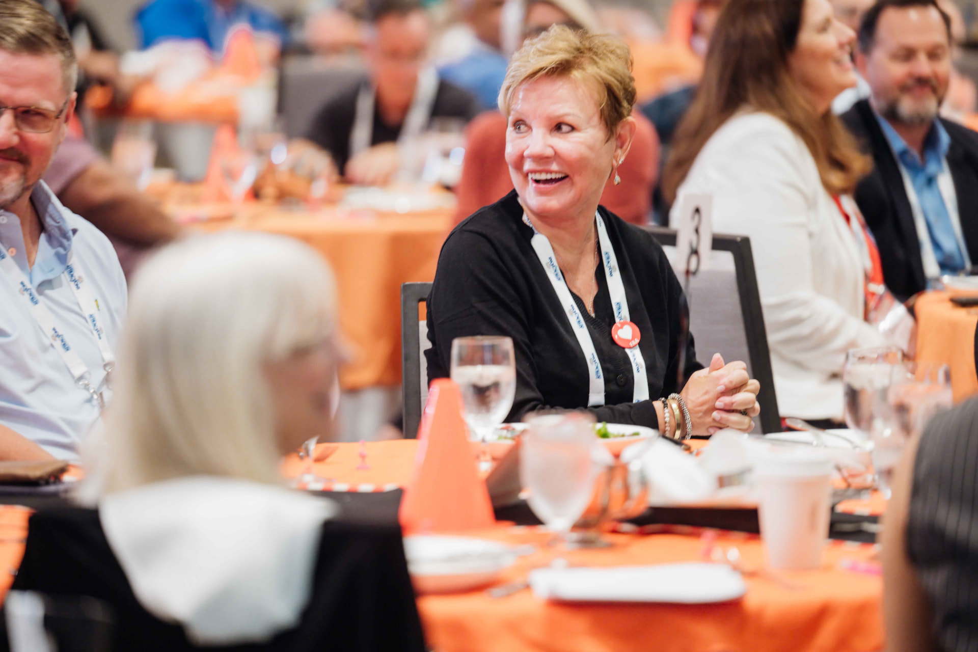 Conference photography of attendees smiling during a seated luncheon session at an Orlando corporate event