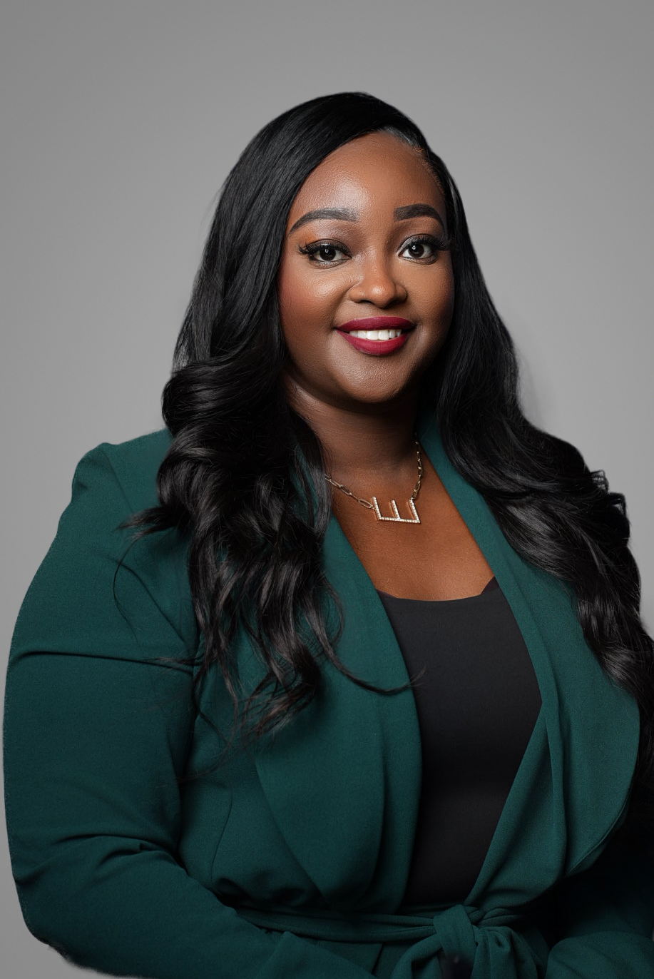 Executive headshot of a businesswoman in an emerald green blazer on a gray studio backdrop