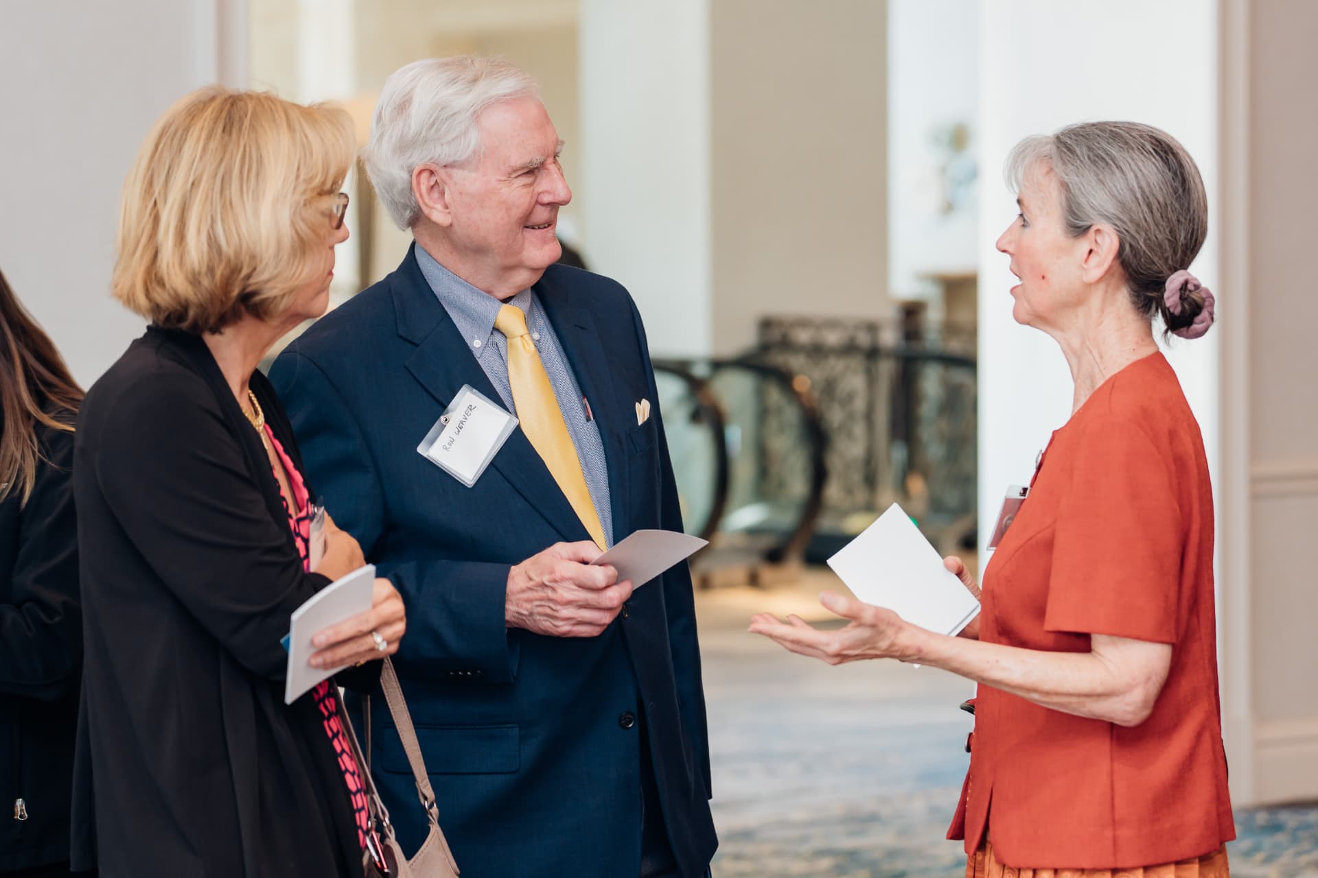 Corporate event photography of executives in conversation during a conference networking break at a hotel venue
