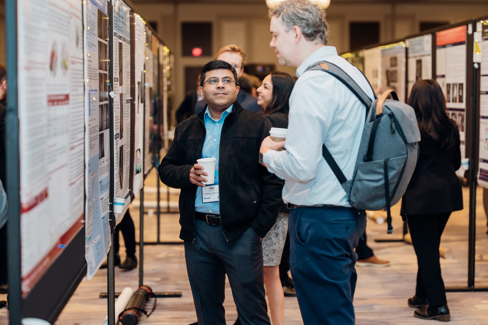 Corporate event photography of conference attendees reviewing research posters during a networking break