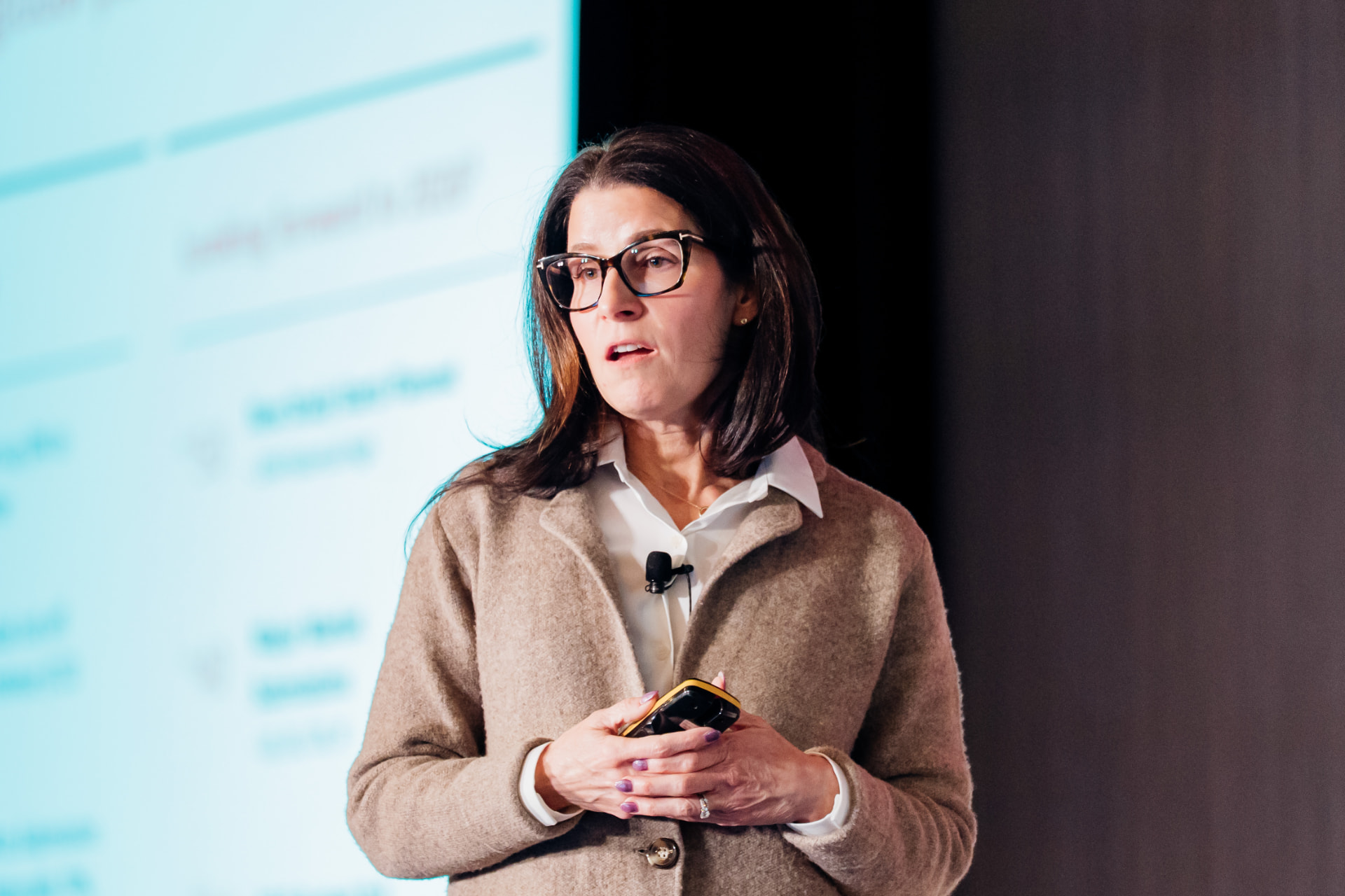 Corporate event photography of a speaker presenting with a clicker in front of a projected slide