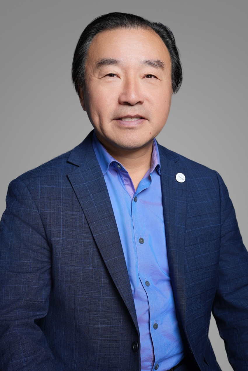 Corporate executive headshot of a business leader in a navy plaid suit on a gray studio backdrop