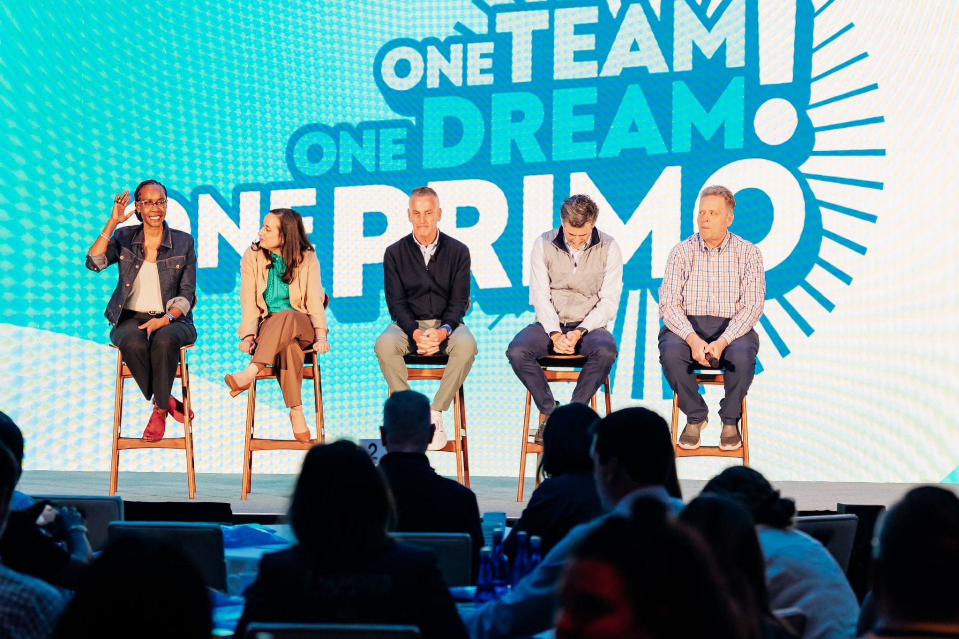 Corporate photography of a leadership panel seated on stage in front of a large LED screen