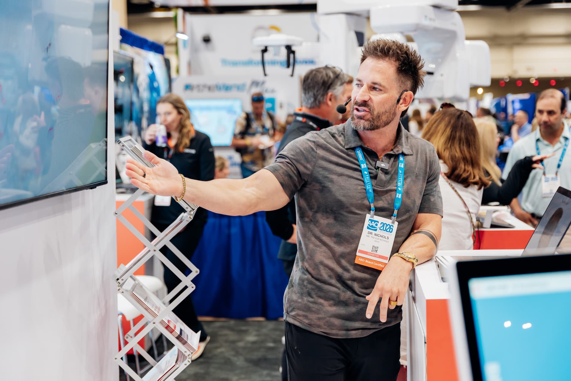 Corporate event photography of an exhibitor with a headset presenting a screen demo at a dental trade show booth